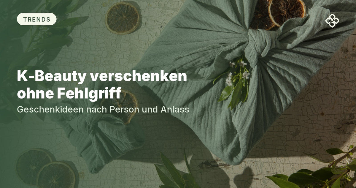 In salbeigrünen Stoff gewickelte Geschenke, daneben getrocknete Orangenscheiben und Grün