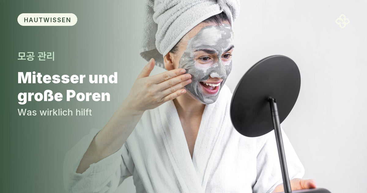 Frau im Bademantel trägt eine graue Tonerde-Maske auf und schaut in einen Spiegel, Purida Ratgeber Mitesser und große Poren