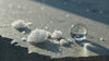 Winterliches Video mit funkelnden Schneekristallen und klaren Eiskugeln auf dunklem Stein – Symbol für Schutz und Feuchtigkeit im Winter.